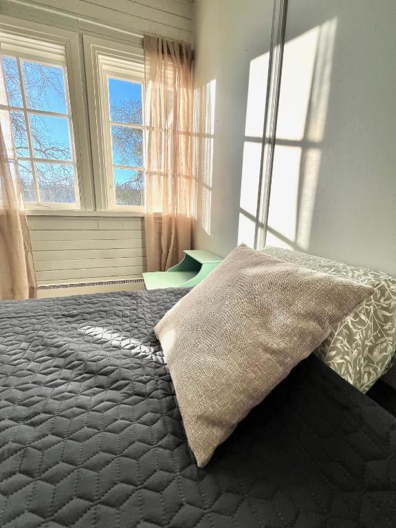 a bedroom with a bed with a blanket and two windows at Vuohensaari, Rantatalo 3 in Salo