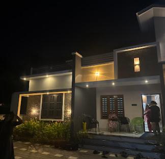 a person standing outside of a house at night at Mermaid Manor in Varkala