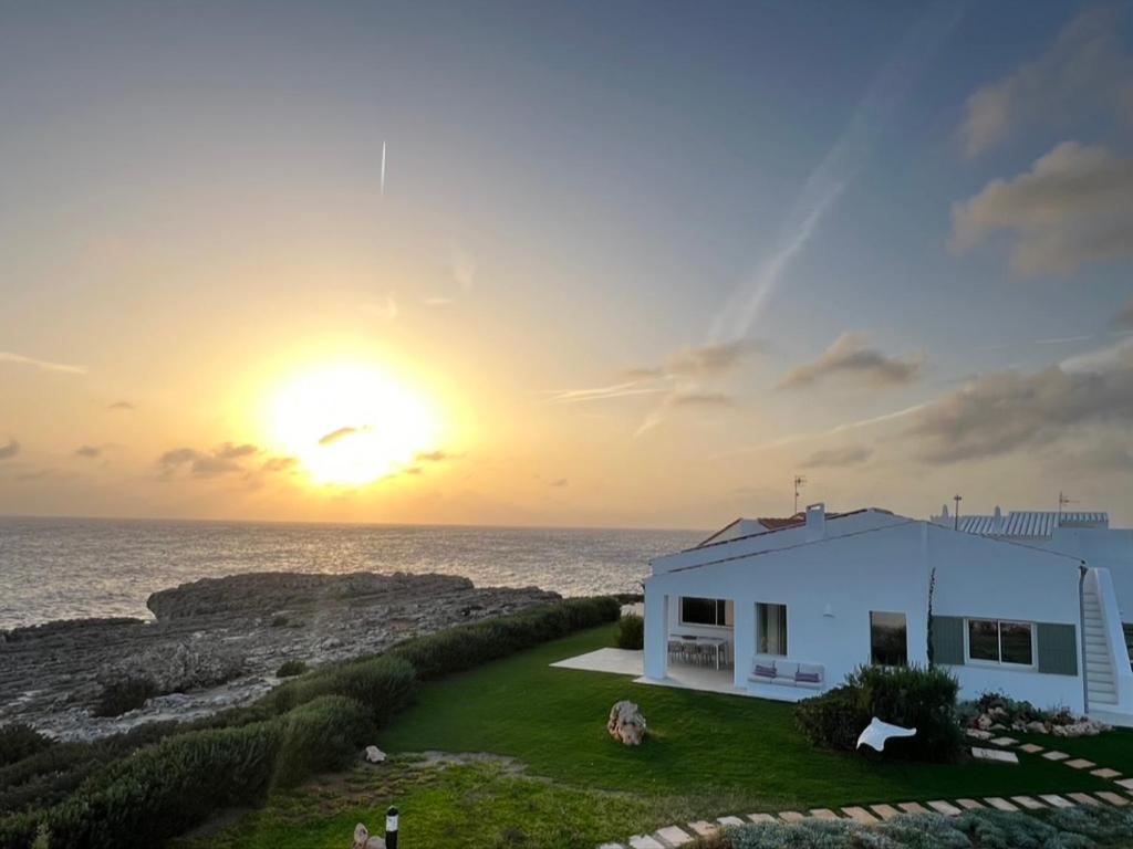 a white house with the sunset in the background at Binilua in Binibeca