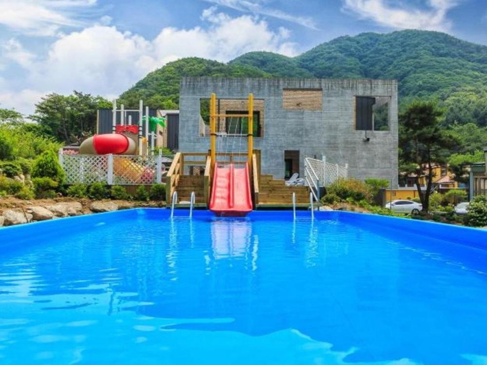 a swimming pool with a slide and a playground at Wonju Cloud Pension in Wonju