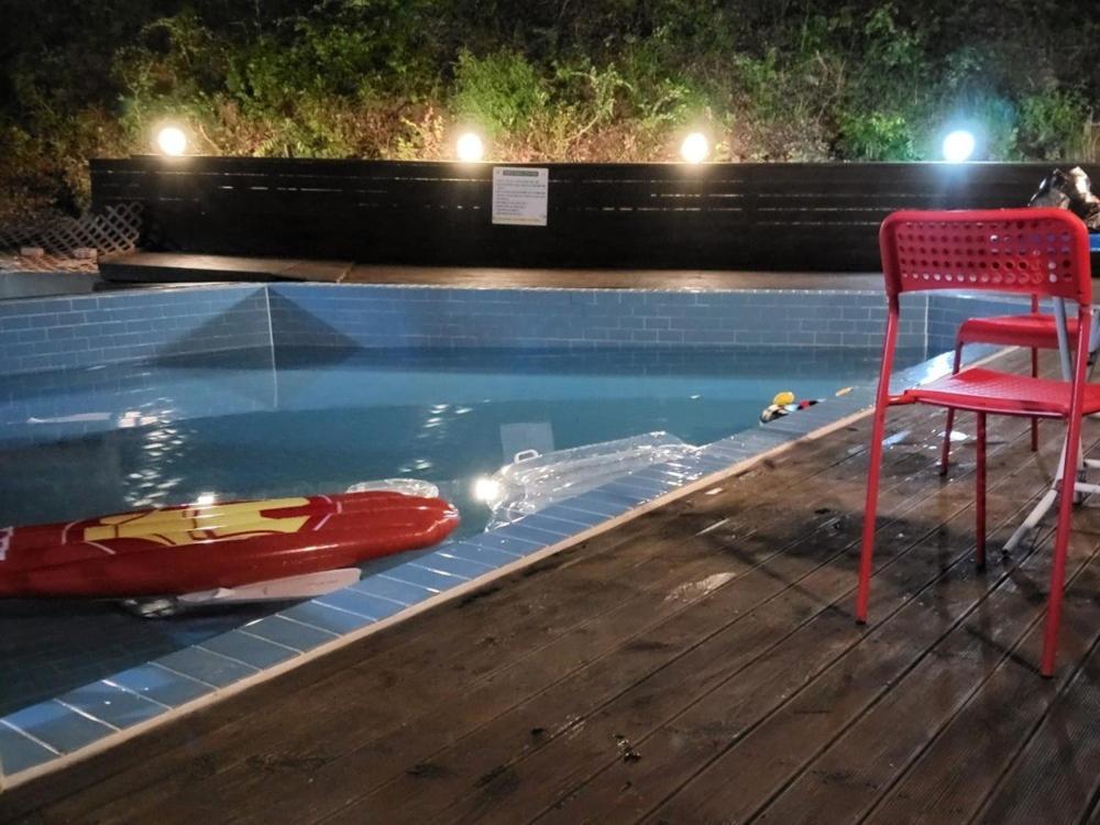 a red chair sitting in a pool with a red boat at Geoje Milky Way Pension in Geoje