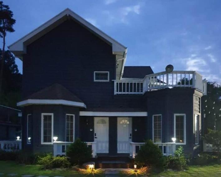 a black house with a balcony on top of it at Pyeongchang underhill pension in Pyeongchang