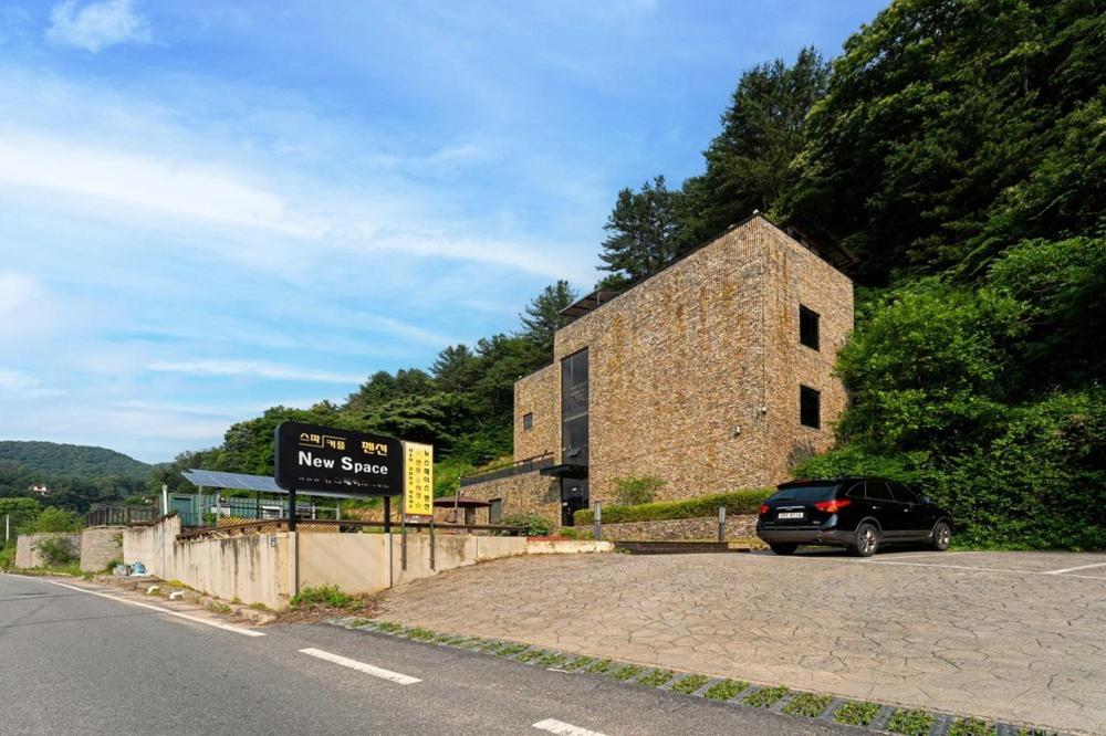 a car parked next to a stone building on the side of a road at Yangpyeong Newspace in Yangpyeong
