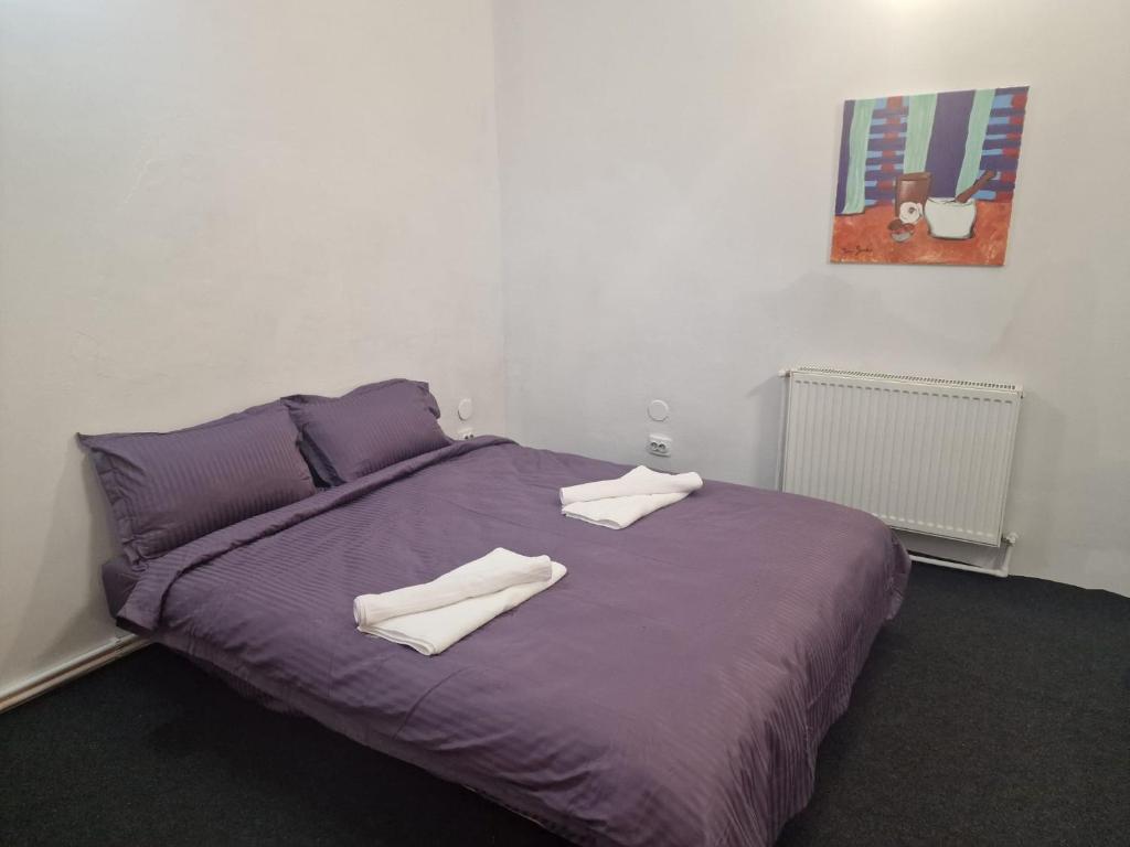 a purple bed with two white towels on it at Eroilor Downtown Studio in Cluj-Napoca