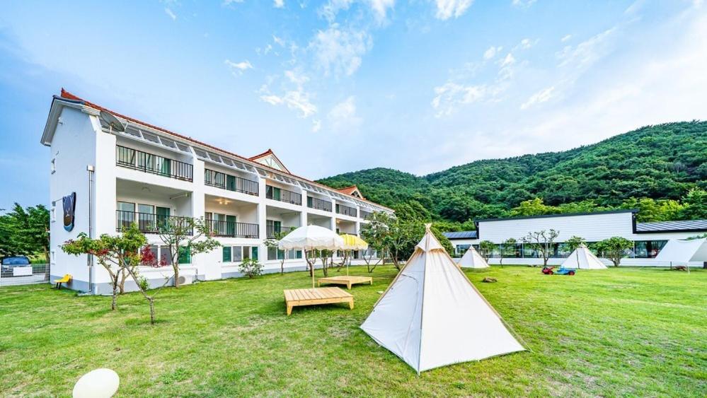 a building with a tent in the grass in front of it at Glamdog - Tongyeong Pet-friendly in Tongyeong