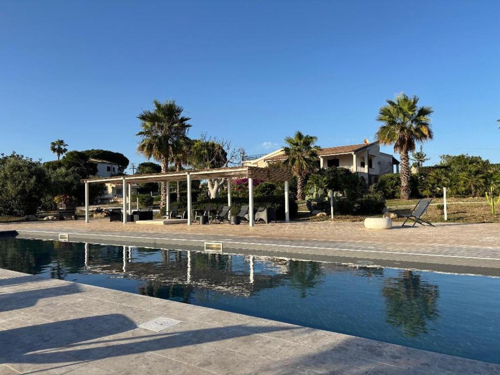 a house with palm trees and a swimming pool at Villa Bianca Plemmirio in Syracuse