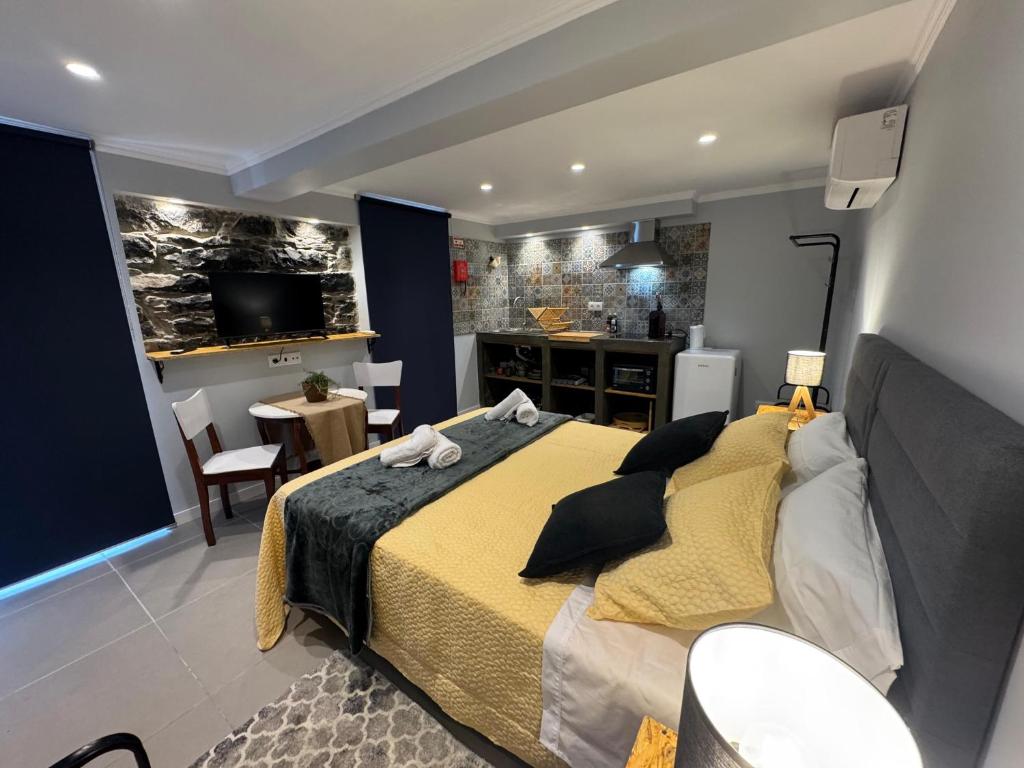 a bedroom with a large bed and a kitchen at Refúgio do Nevoeiro Estudio in Porto Moniz