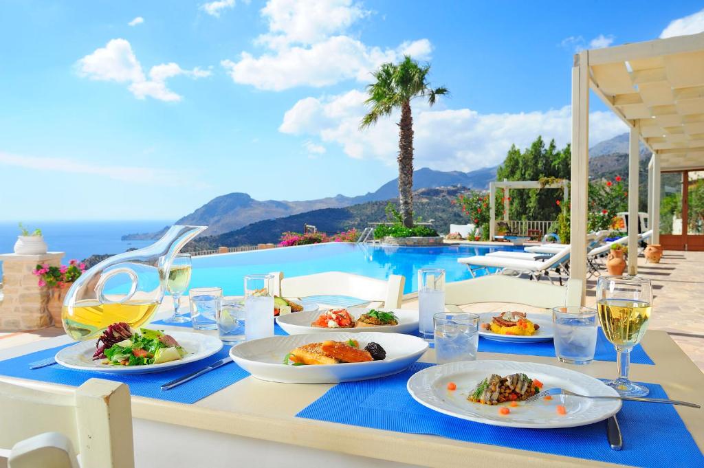 a table with plates of food on it next to a pool at Stefanos Village Hotel in Plakias