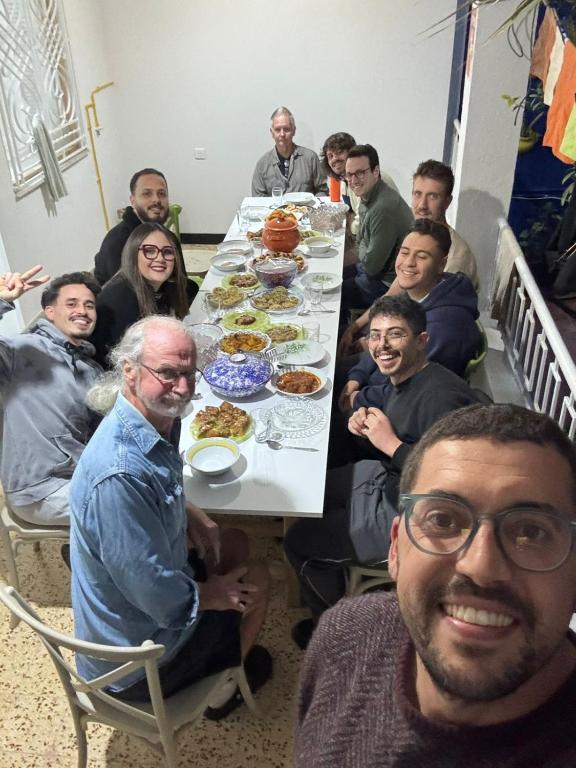 a group of people sitting around a table with food at Nomads Hostel Sousse in Sousse