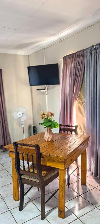 a wooden table and bench with a vase of flowers on it at Marli Guesthouse Self-Catering in Welkom