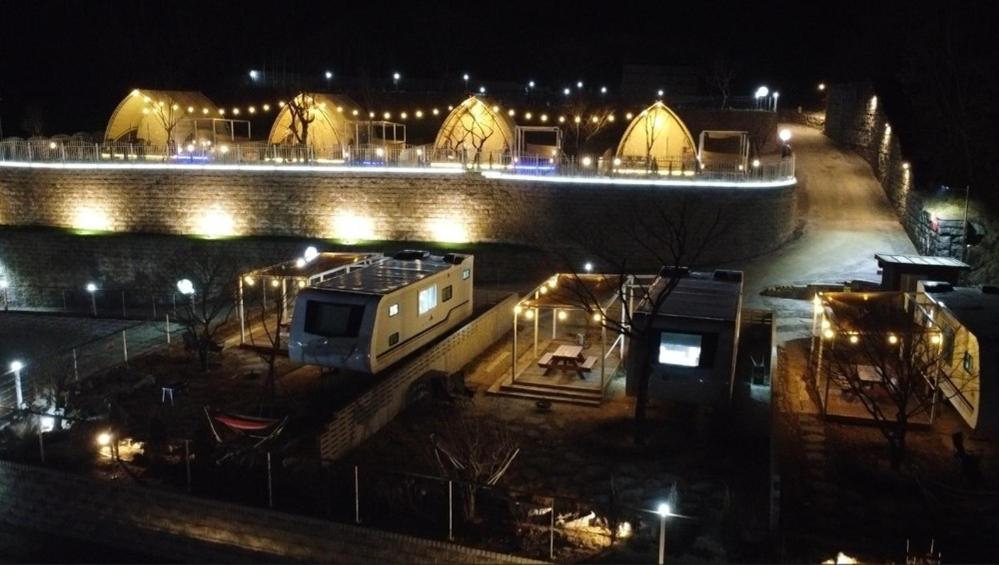 a city at night with a bridge and lights at The Hill Glamping in Yeoju