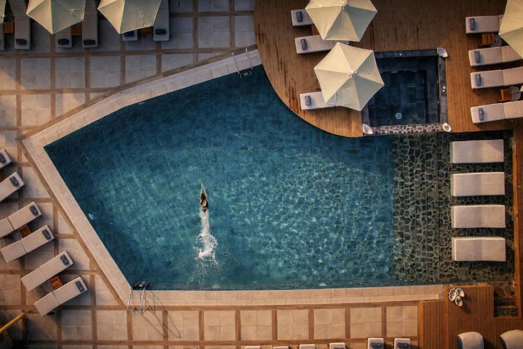 an overhead view of a pool with a person in the water at Elounda Orama by GHH in Elounda