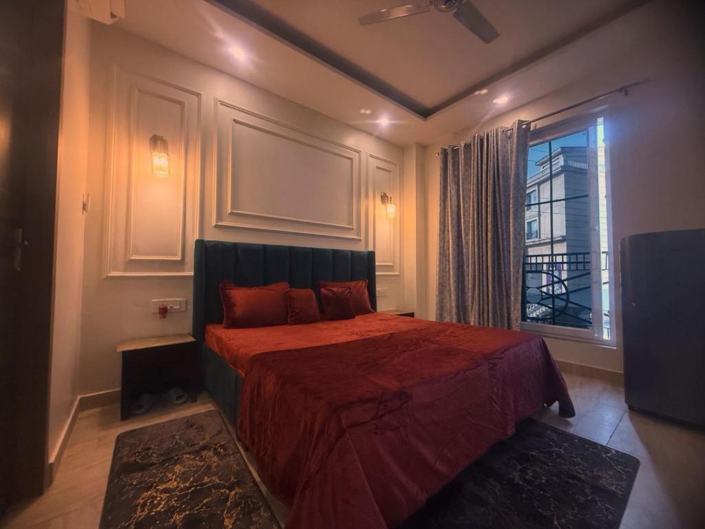 a bedroom with a bed with a red comforter and a window at Mahadev Hotel in Zirakpur