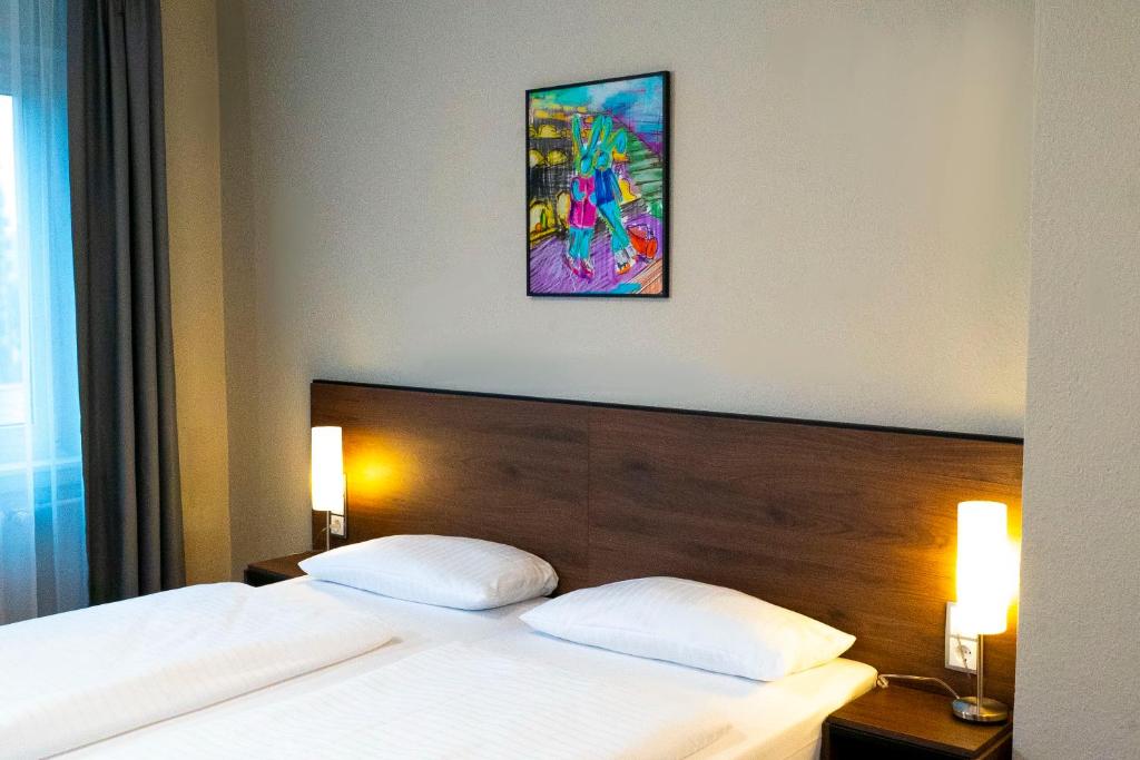 a bed with two white pillows and a painting on the wall at Fair Hotel Europaallee in Frankfurt