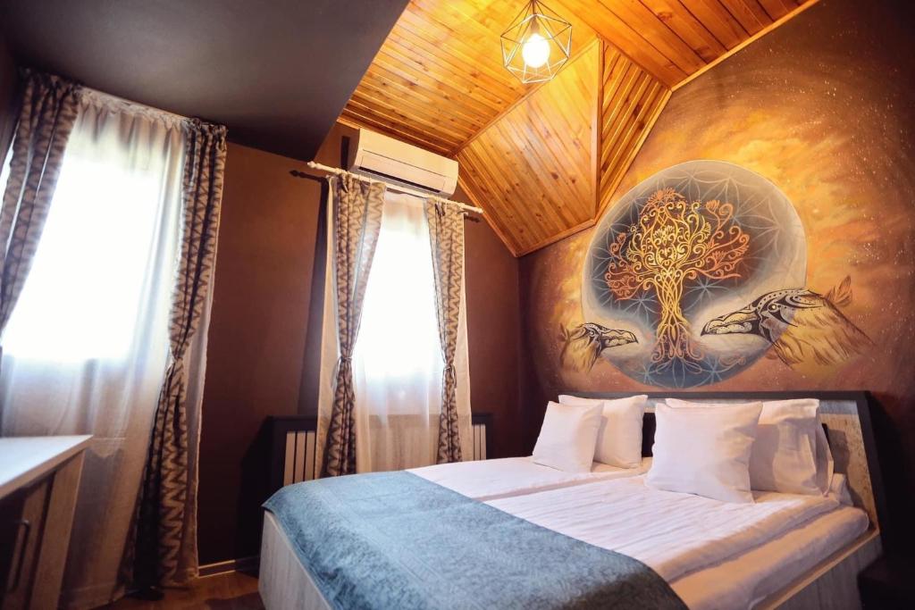 a bedroom with a bed with a painting on the wall at Pensiunea Dezire in Baile Unu Mai