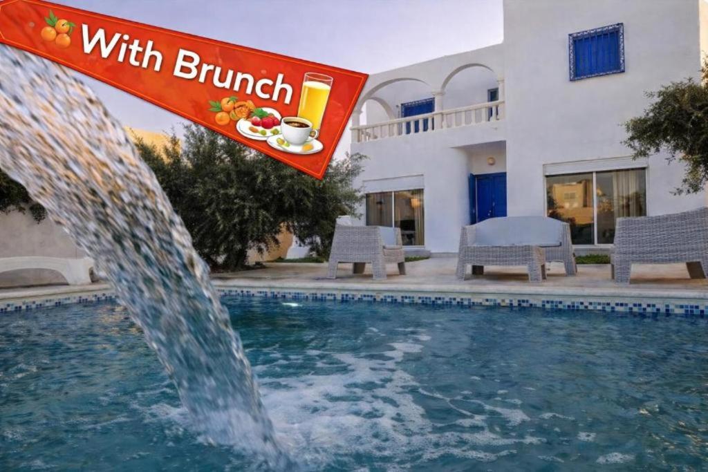 a pool with a fountain in front of a building at Djerba 7 in Aghīr