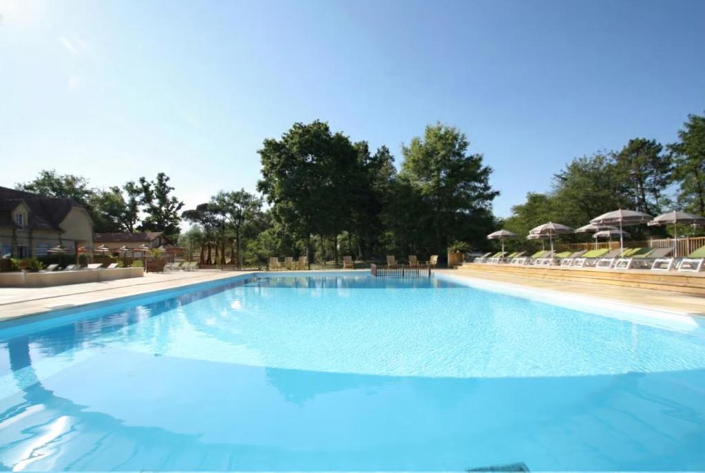 a large blue swimming pool with chairs and umbrellas at Camping Le Soleil des Landes in Lit-et-Mixe