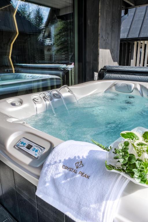 a jacuzzi tub with a towel and plants in it at Crystal Peak Villas z prywatnym jacuzzi, Odkryj-Zakopane in Kościelisko