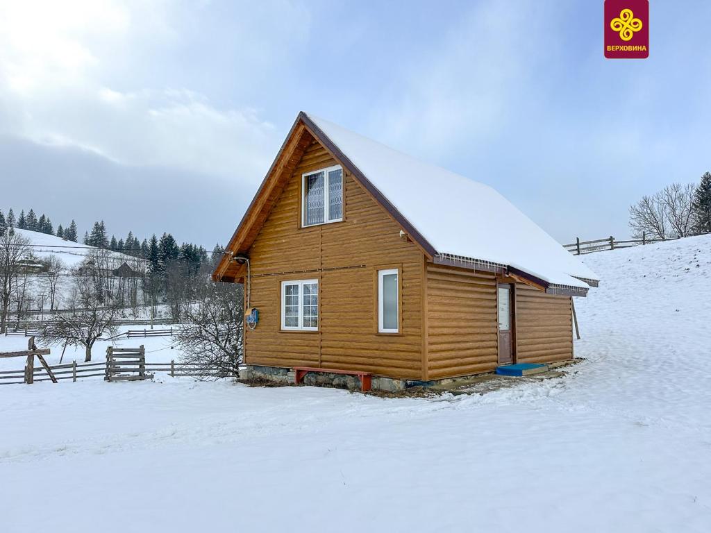 a wooden house with snow on the roof in the snow at Трофейна хатина in Krivopolʼye