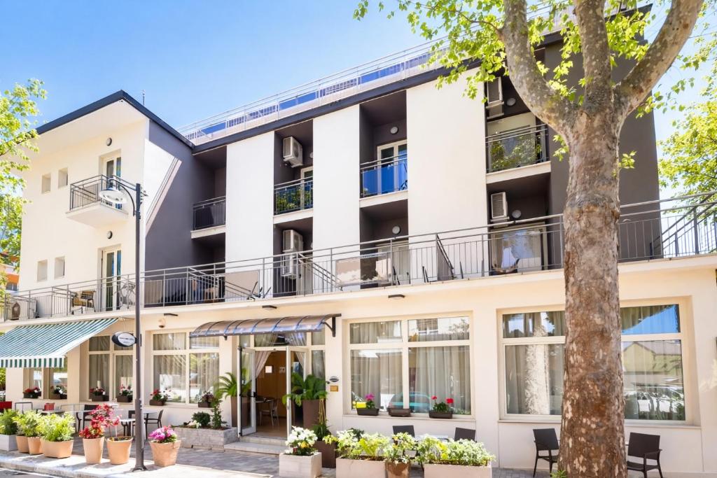 an apartment building with windows and a tree at Hotel Villa Tina Easy Stay B&B in Cesenatico