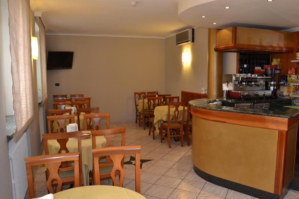 un restaurante con bar y algunas mesas y sillas en Hotel Cavour, en Asti