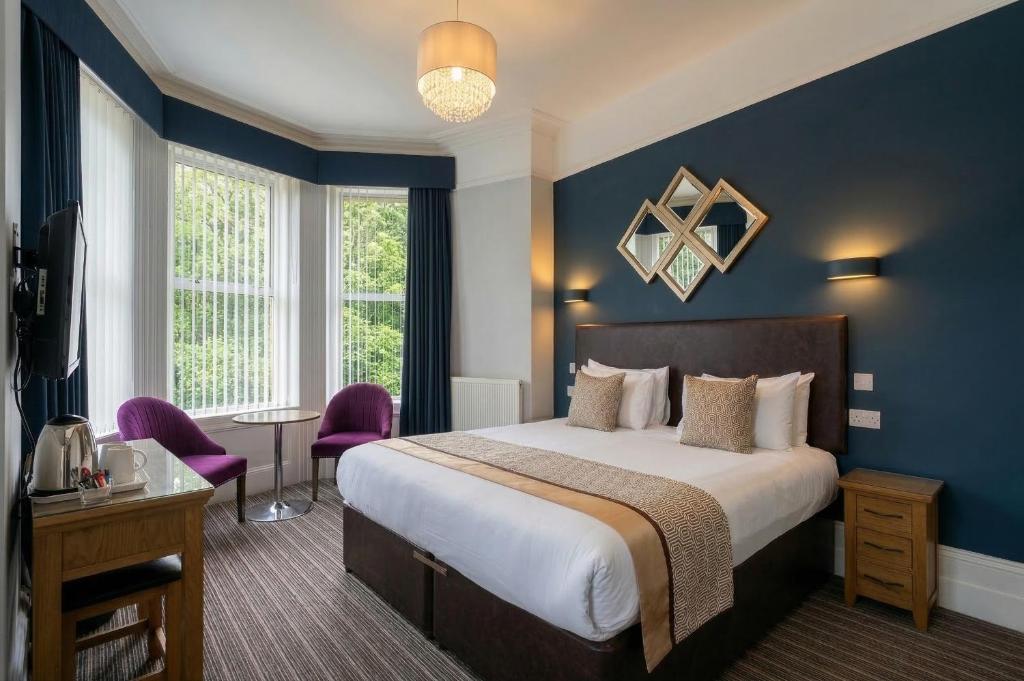 a bedroom with a large bed with blue walls at Applewood Hotel in Bournemouth