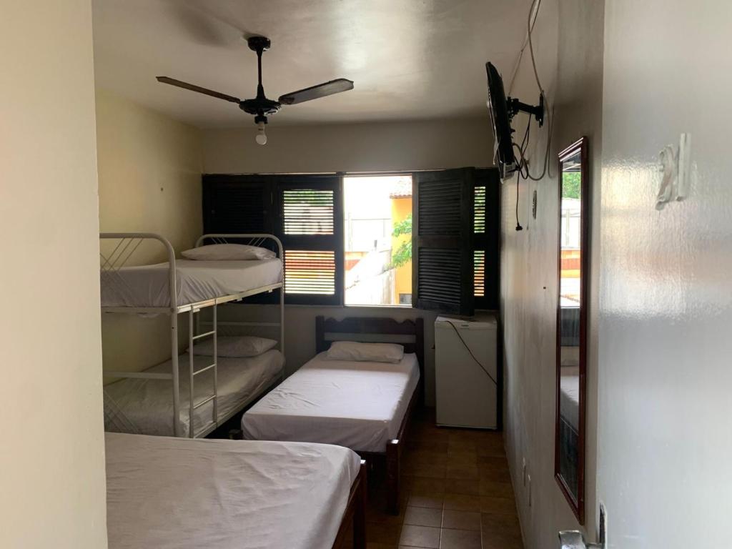 a room with three beds and a ceiling fan at Pousada Malu in Fortaleza
