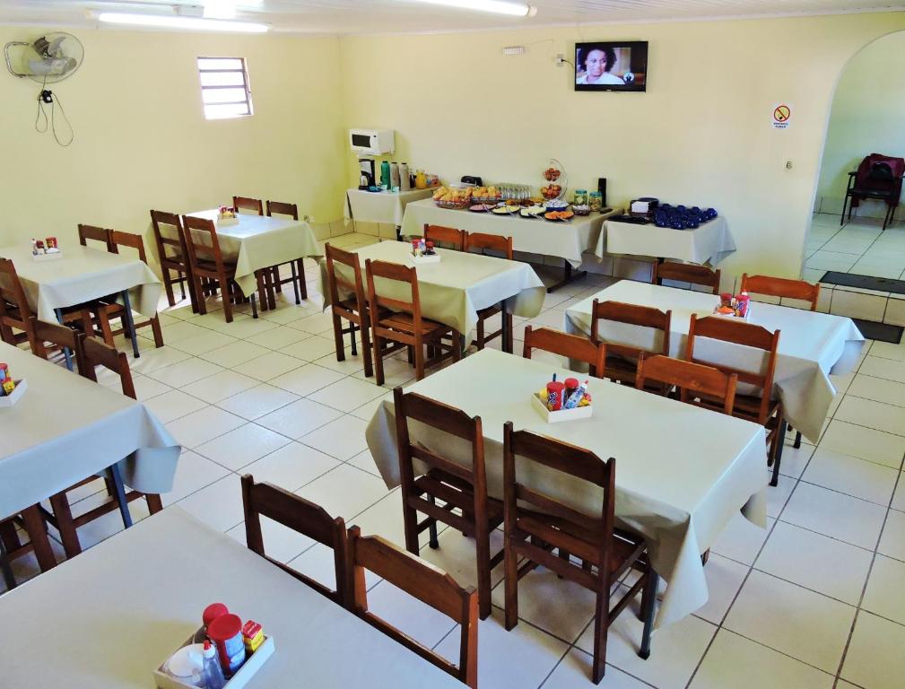 un comedor con mesas blancas y sillas de madera en Hotel Comodoro De Livramento, en Santana do Livramento