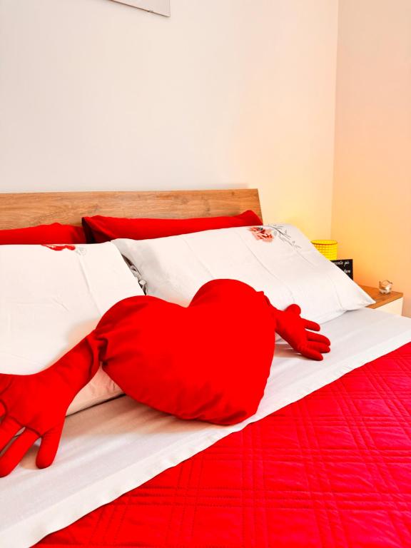 a red heart pillow laying on a bed at Petali Rosa - Dimora Antica Roma in Polignano a Mare