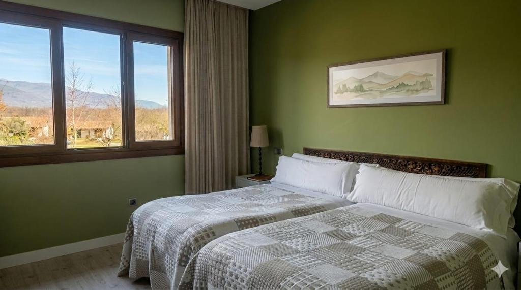 a green bedroom with a bed and a window at Hotel El Mirlo Blanco in Candeleda