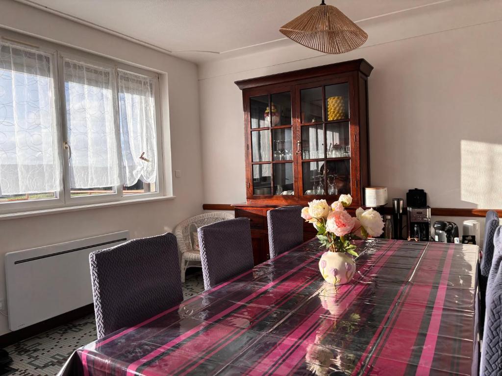 a dining room table with a vase of flowers on it at Gîte Les Mirabelliers à Morville Hébergement cosy in Morville