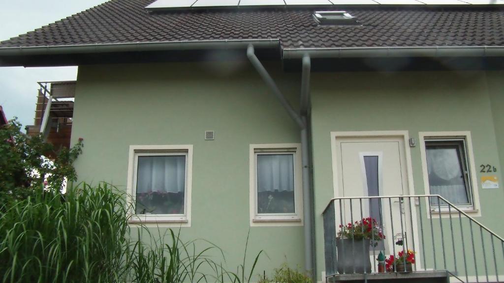 a green house with two windows and a balcony at Ferienwohnung Am Bahnhof in Hochkirch
