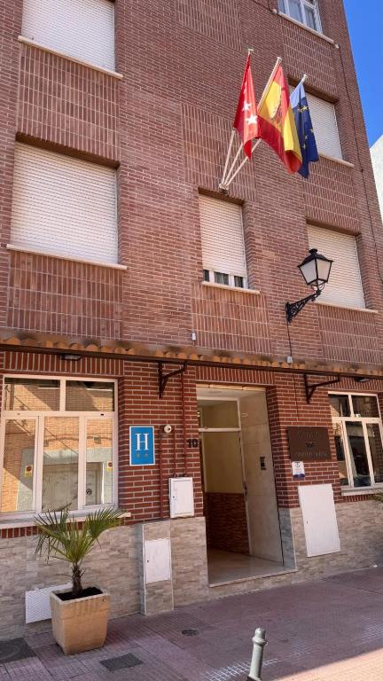a brick building with two flags hanging from it at Hotel Cuatro Caños in Alcalá de Henares