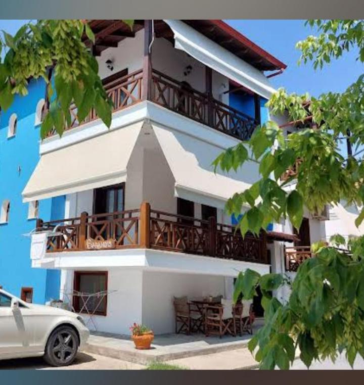 a building with a balcony and a car parked in front at Hotel Sarandos in Ammouliani