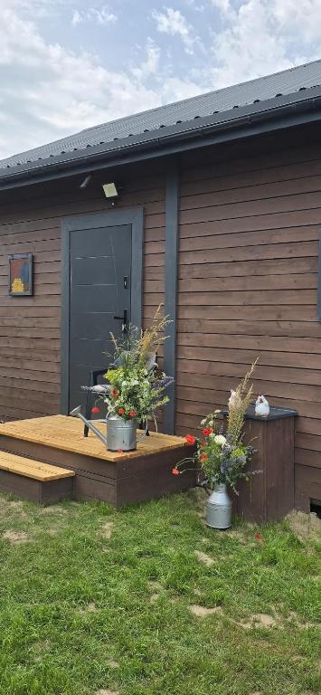 a wooden deck with two potted plants in front of a house at Domki u Sołtysa in Ciechocinek