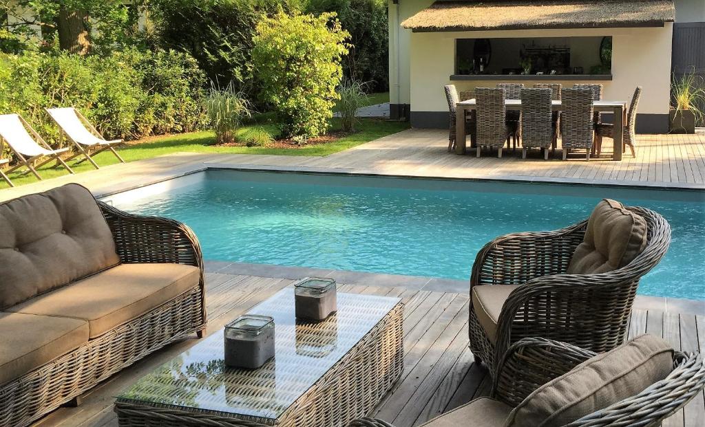 uma piscina com duas cadeiras de vime e uma mesa num deque em Villa d'hôtes Graine de Pin em Le Touquet-Paris-Plage