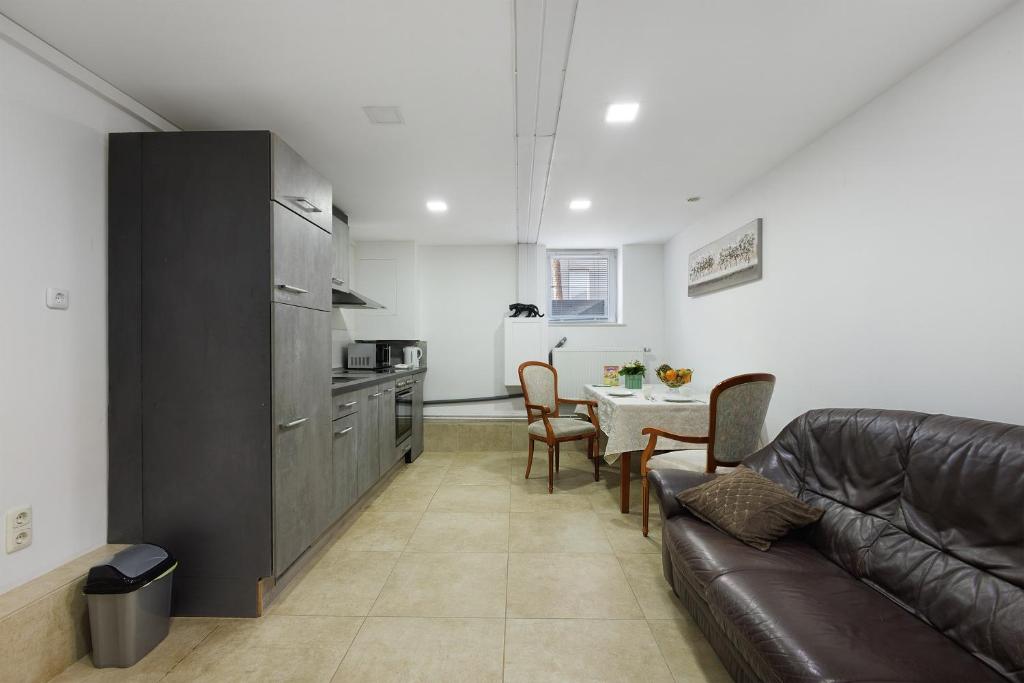 a living room with a leather couch and a kitchen at Ferienwohnung Tiefer Garten in Itzehoe