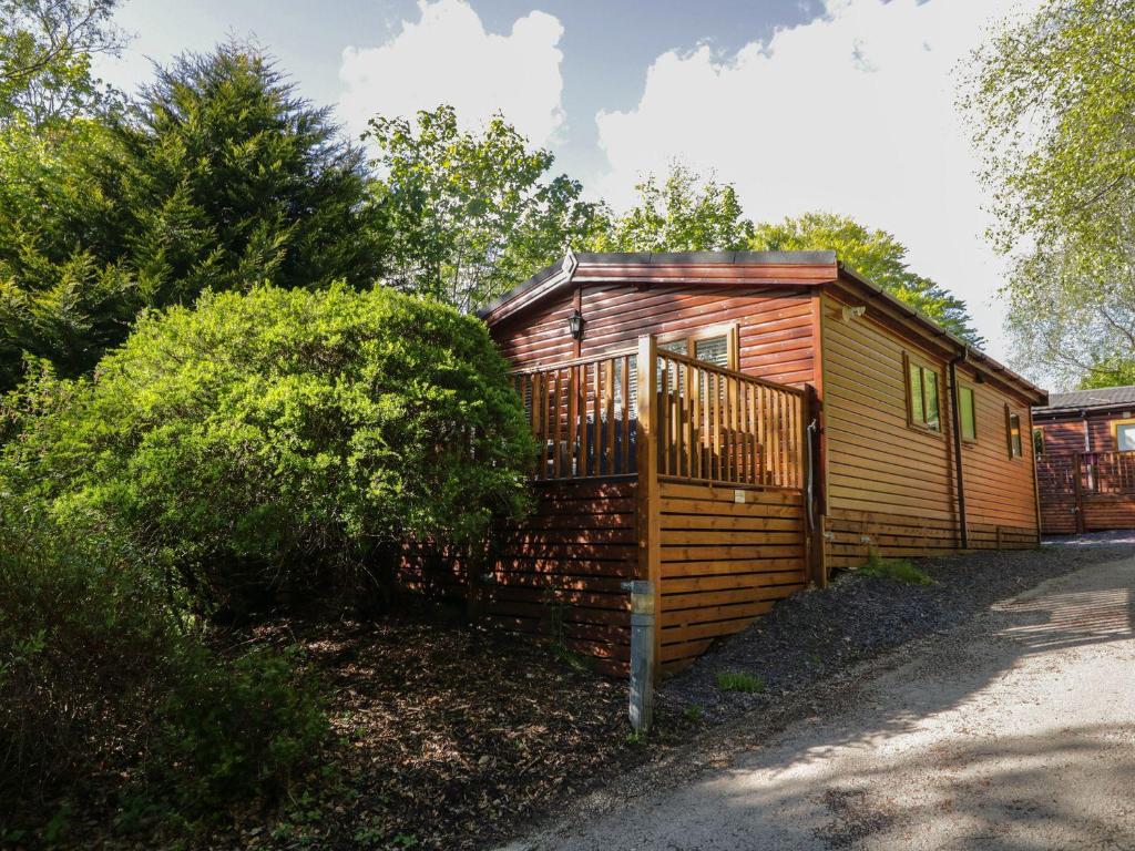 a small wooden cabin with a gate on a street at Mere Brook Lodge in Windermere