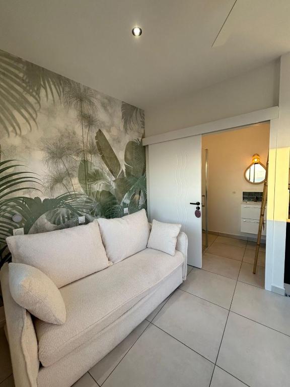 a living room with a couch and a painting on the wall at le paradis vert bleu in Saint-Paul