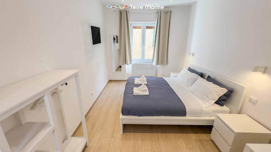 ein kleines weißes Schlafzimmer mit einem Bett und einem Fenster in der Unterkunft Sapri 29, Terre Marine in La Spezia