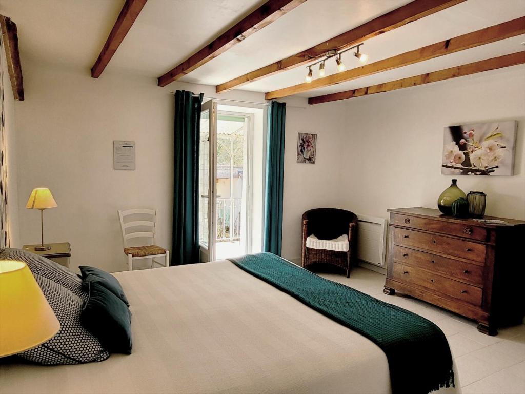 a bedroom with a bed and a dresser and a window at Le Mas Cauvy in Saint-Christol-lès-Alès