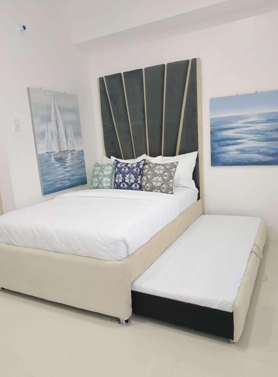 two beds in a white room with paintings on the wall at WV Tower 3rd Floor in Iloilo City