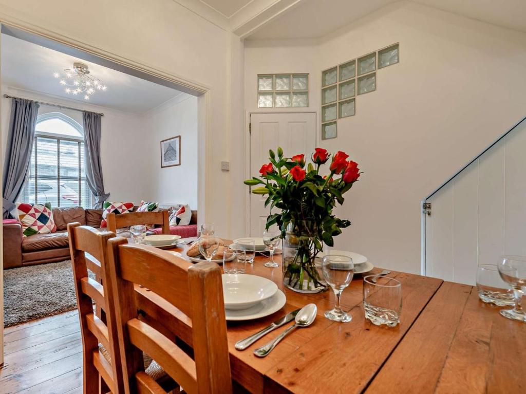 a dining room with a wooden table with red flowers at 3 Bed in Newquay oc-53688 in Newquay