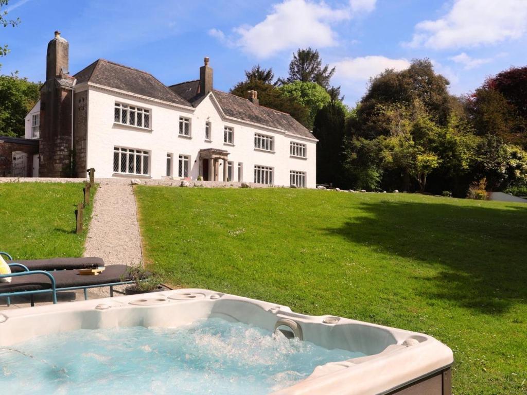 a large white house with a hot tub in the yard at 8 Bed in Newquay oc-81510 in Saint Columb Major