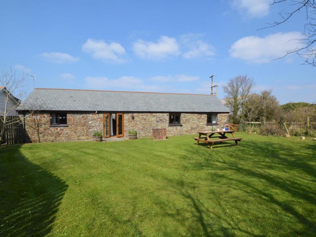 a stone house with a picnic table in the yard at 2 Bed in Bude oc-coryb in Morwenstow