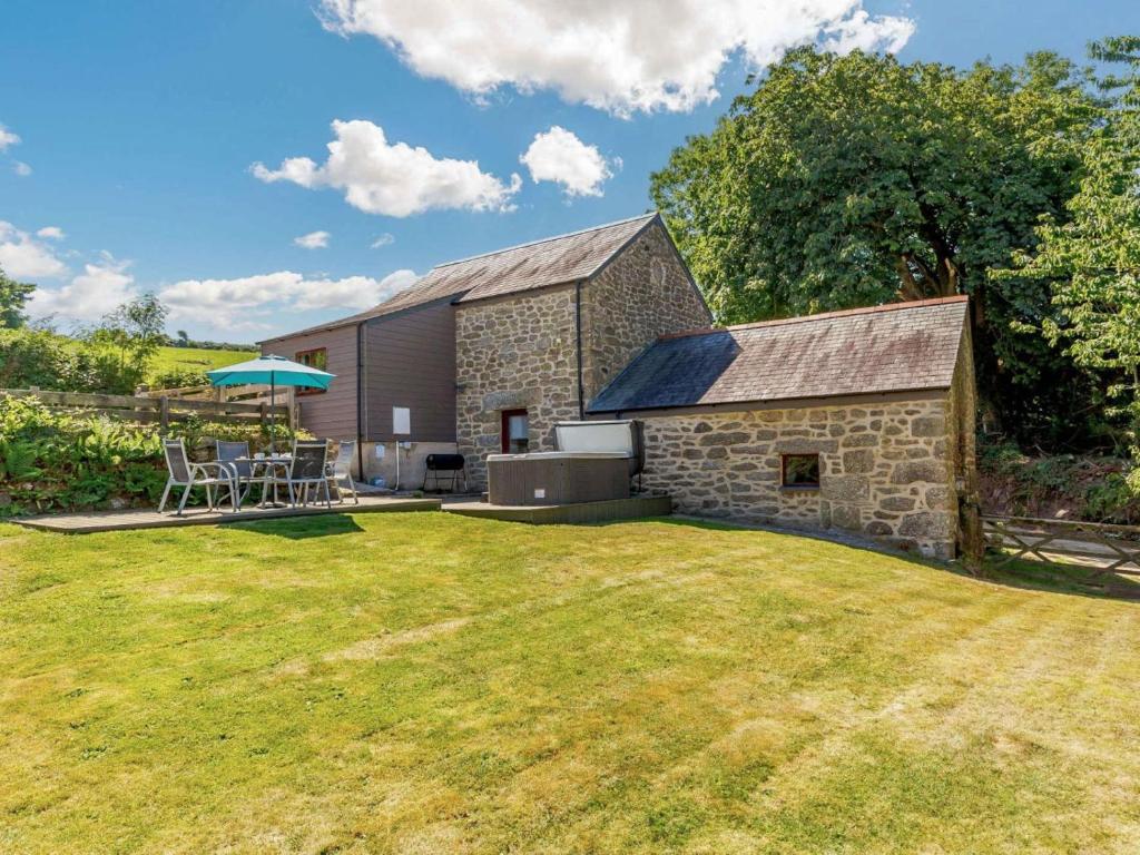 a stone barn with a table and an umbrella at 2 Bed in Bodmin oc-chest in Lanlivery