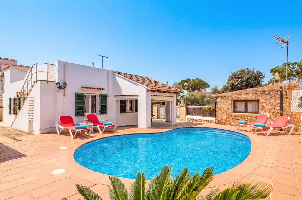 a villa with a swimming pool and red chairs at Villa Rincon by Villa Plus in Cala Blanca