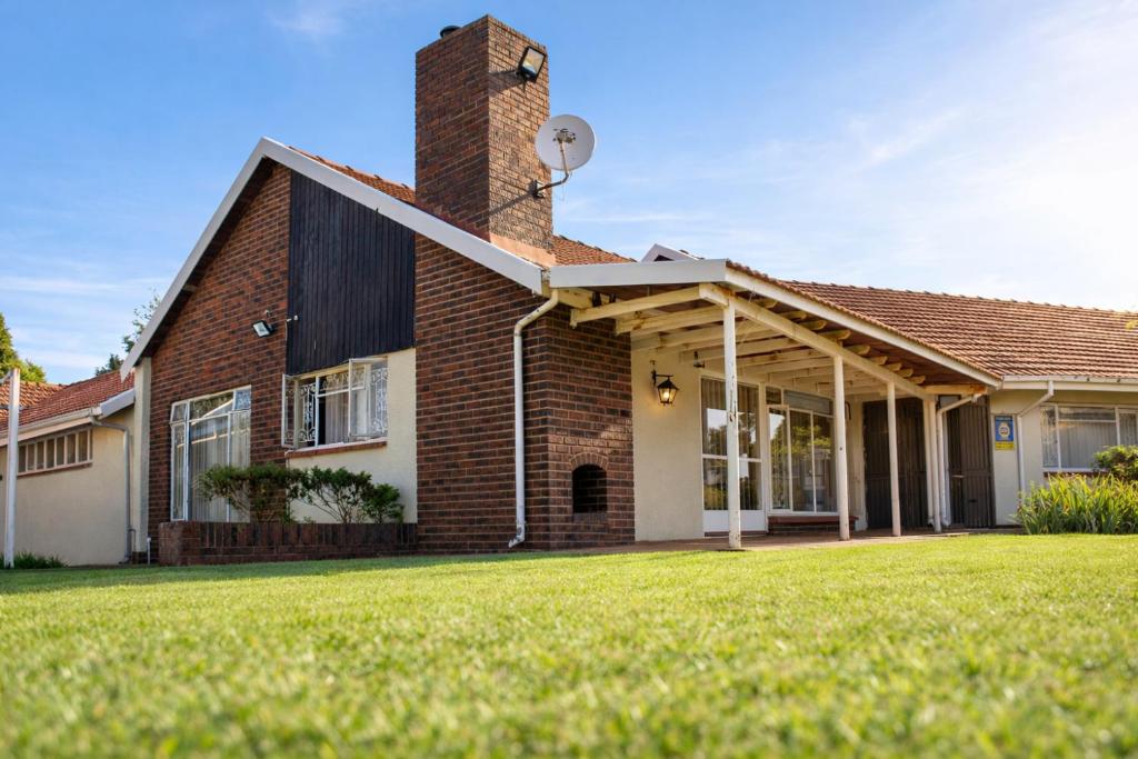 a brick house with a grass yard at Spacious Holiday Home in Florida Park! Pool! Parking! Fast Wifi! in Roodepoort