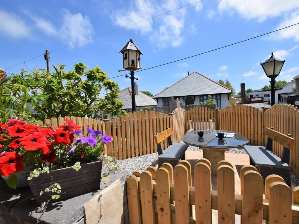 a backyard with a wooden fence and a table and flowers at 1 Bed in Wadebridge oc-42756 in Wadebridge