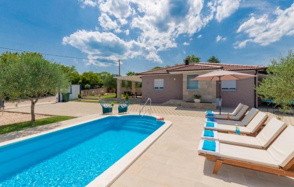 a swimming pool with chairs and a house at Villa Korana with heated Pool & Jacuzzi in Kamenmost
